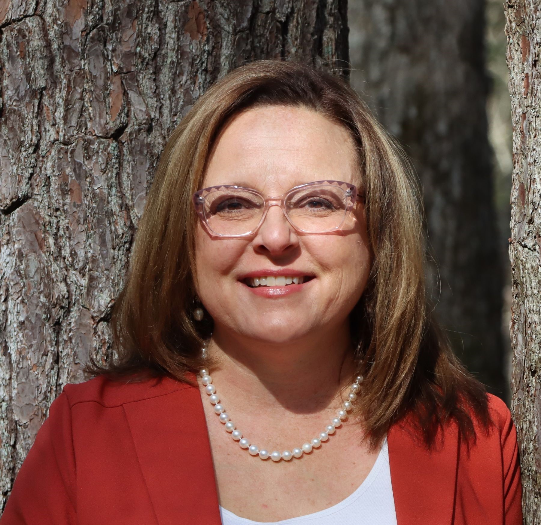 Angeleigh Dorsey in red blazer stands by a tree