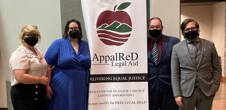 Attorneys stand next to an AppalReD sign after helping clients at an expungement clinic.