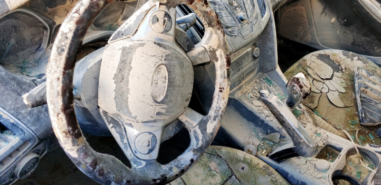 A car's steering wheel and seats are covered with dry mud.